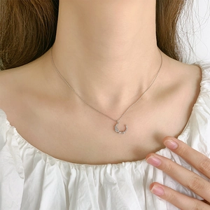 Collier lune en argent élégant serti de zircones porté par une femme sur fond blanc