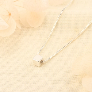 Minimalist s925 silver cube pendant on box chain necklace over soft textured fabric