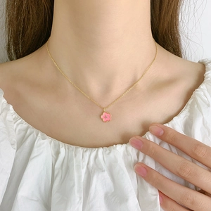 Pink cherry blossom necklace in gold finish worn on a white ruffled shirt for women