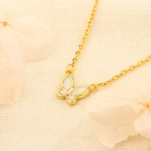 Élégant collier papillon doré avec émail blanc sur un fond beige à la mode chic