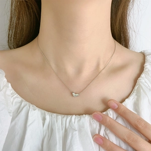 Textured silver heart pendant necklace on minimalist chain worn on collarbone