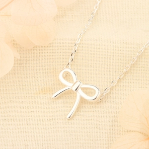 Minimalist silver bow pendant necklace on a delicate cross chain for women