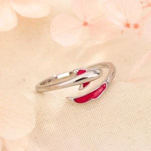 Adjustable silver koi fish ring featuring red enamel details on textured beige fabric