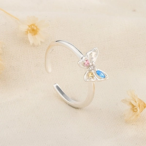 Macro detail of adjustable butterfly ring featuring colorful pear-shaped gemstones