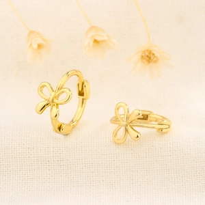 Elegant gold bow earrings on a textured fabric background with dried flowers