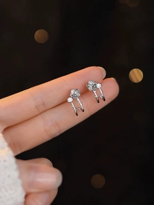 Detailed view of silver camellia earrings with sparkling stones held by fingers