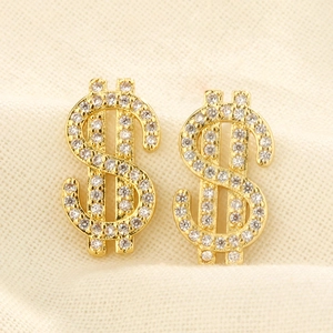 Detailed close-up of gold dollar sign stud earrings with shimmering zircon pavé stones