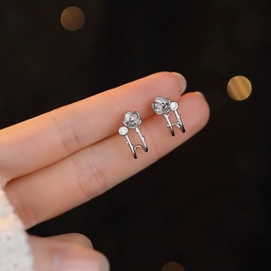 Silver camellia flower earrings with sparkling zircon center on dark background