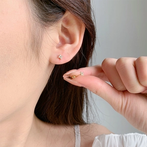 Detail of gold flower stud earrings with zircons and secure screw ball backs