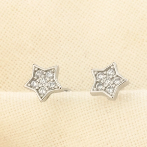 Gros plan de boucles d'oreilles étoile en argent avec zircons sur tissu beige texturé