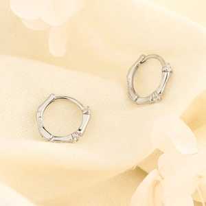 S925 sterling silver bamboo hoop earrings with sparkling cubic zirconia on a petal background