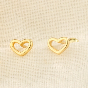 Macro shot of S925 silver hollow heart earrings in gold finish on textured fabric