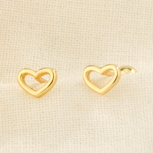 Elegant gold hollow heart stud earrings with secure screw backs on textured beige fabric