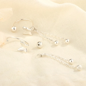 Detail of silver butterfly ear cuffs with detachable double chain fringe on linen cloth