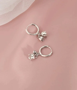 Dettaglio degli orecchini a mughetto in argento S925 con marchio su sfondo di raso rosa