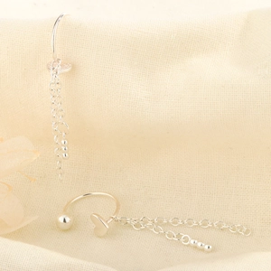Silver heart screw earrings with tassel chain pendants on beige linen background