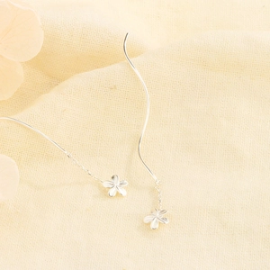 Detailed macro view of S925 sterling silver flower tassel drop earrings on linen fabric
