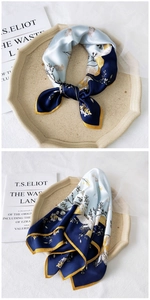 Detailed view of a silk scarf featuring blue floral prints and elegant yellow hand-rolled edges
