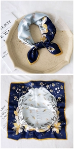 Detail view of a silk square scarf featuring nautical shells and floral prints in blue and yellow