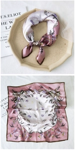 Detail of silk square scarf showing purple floral patterns and satin texture on a tray