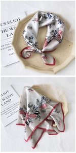Macro detail of silk square scarf with floral prints and red rolled edge on a book
