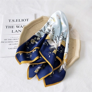 French vintage blue silk scarf with floral and shell patterns on a beige ceramic plate