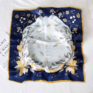 Navy and ginger floral silk square scarf with seashell patterns on a white linen surface