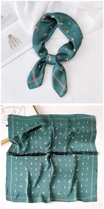 Close-up of a dark green silk square scarf featuring detailed dog prints and yellow borders