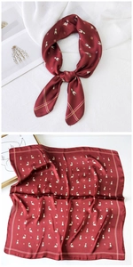 Detail of burgundy silk scarf with small dog patterns and geometric logo motifs
