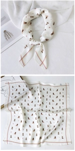 Detail of silk square scarf showing puppy print and branding on beige fabric