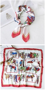 Detailed view of square silk scarf with equestrian horse print and red borders