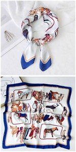 Detail of a square silk scarf featuring blue edges and elegant equestrian prints