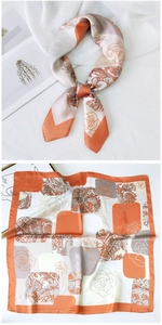 Detail of elegant orange and beige square silk scarf with paisley and rose patterns