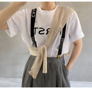 Detail eines gestreiften Strickschals über T-Shirt und grauer gestreifter Hosenträgerhose