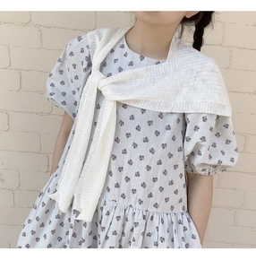 Detail eines weiß gestreiften Strickschals, gebunden über ein florales Kleid mit Puffärmeln
