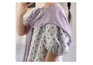 Detail eines hellvioletten gestreiften Strickschals über einem weißen Blumen-Sommerkleid