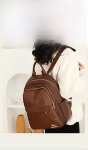Detail of dark brown leather backpack featuring woven texture and golden metal hardware