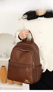 Detail of dark brown textured leather backpack with gold kangaroo logo and zipper hardware