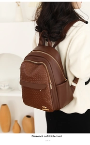 Detail of woven leather texture and golden zippers on a dark brown backpack for women