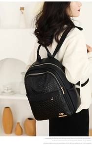 Close-up of black leather backpack featuring gold kangaroo logo and embossed animal texture