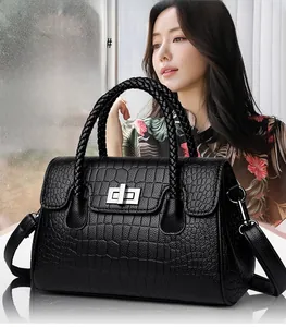 Detail of black crocodile texture handbag with woven handles and silver twist lock closure