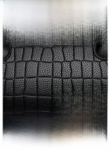 Detail of black oil wax leather handbag featuring crocodile embossed texture and silver lock