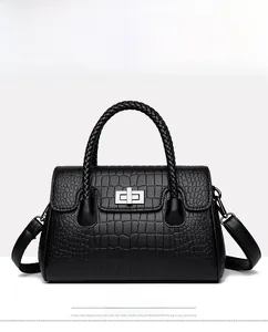 Detail of black faux crocodile leather handbag with woven handle and silver lock hardware