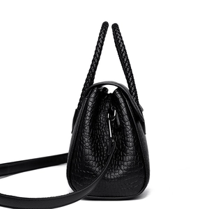 Elegant black crocodile pattern handbag with woven handles and crossbody strap