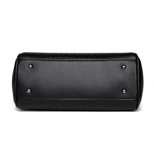 Bottom view of black leather handbag with crocodile pattern and silver metal base studs