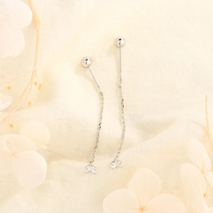 Close-up of elegant silver tassel earrings with zircons on a rustic fabric background