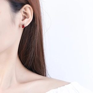 Exquisite red rabbit stud earrings with silver details on a female model's ear