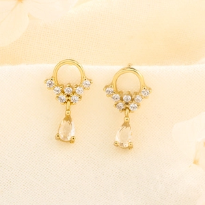 Macro view of gold drop earrings with sparkling cubic zirconia on a linen fabric