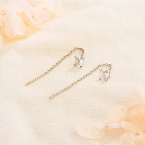 Detail of S925 silver heart tassel earrings with sparkling zircon on textured beige fabric
