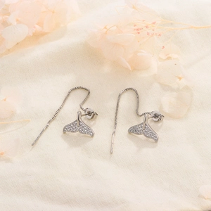 Macro detail of silver fishtail ear threads with sparkling zircons on linen background